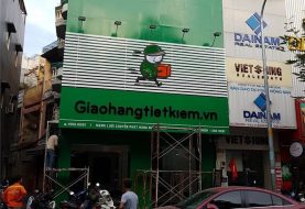 Mặt tiền bưu cục Giao Hàng Tiết Kiệm: lam trắng, bảng alu xanh, nhân vật nổi