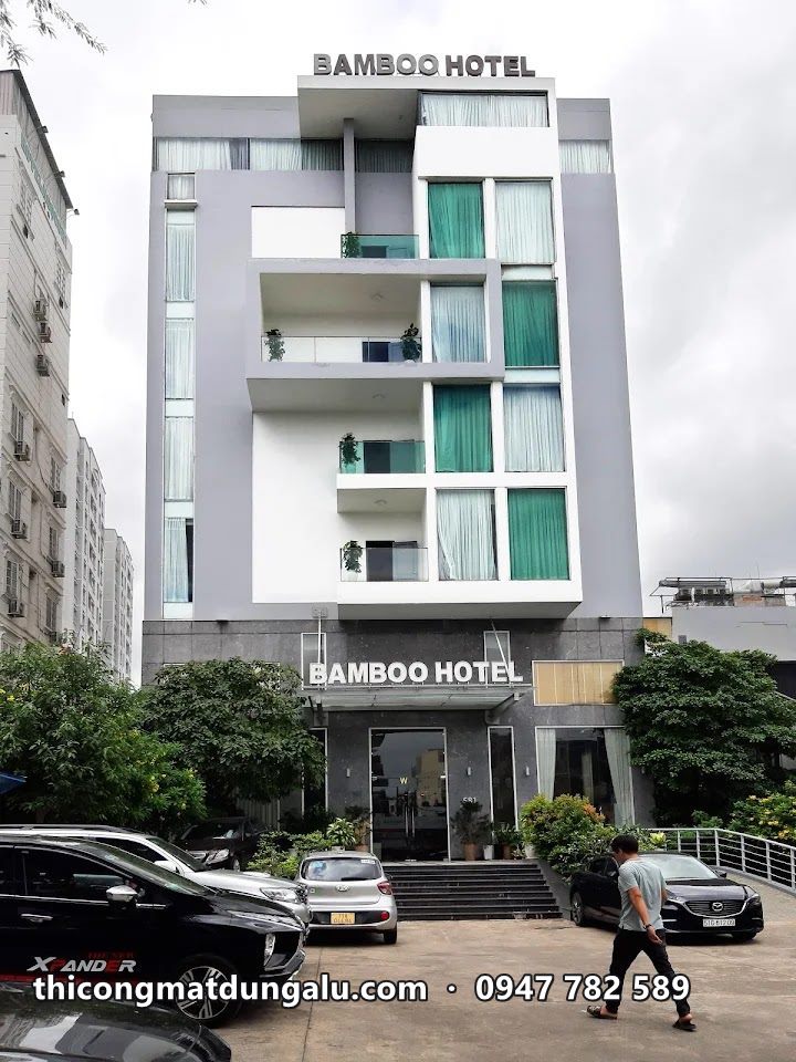 Tòa nhà khách sạn Bamboo Saigon nhiều tầng với mặt tiền trắng xám và kính xanh