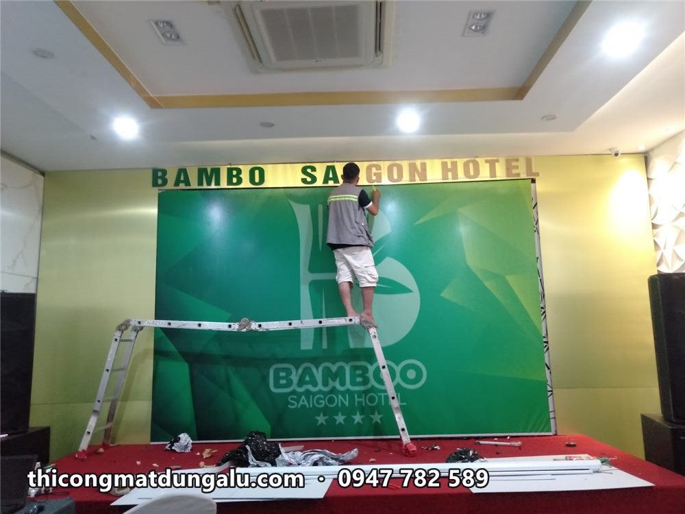 Toàn bộ tường sân khấu với phông xanh và dòng chữ nổi phía trên, thang vẫn còn trên sân khấu