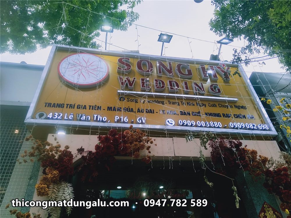 Bảng hiệu Song Hỷ Wedding hoàn thiện ban ngày với logo tròn, chữ đỏ, viền trắng