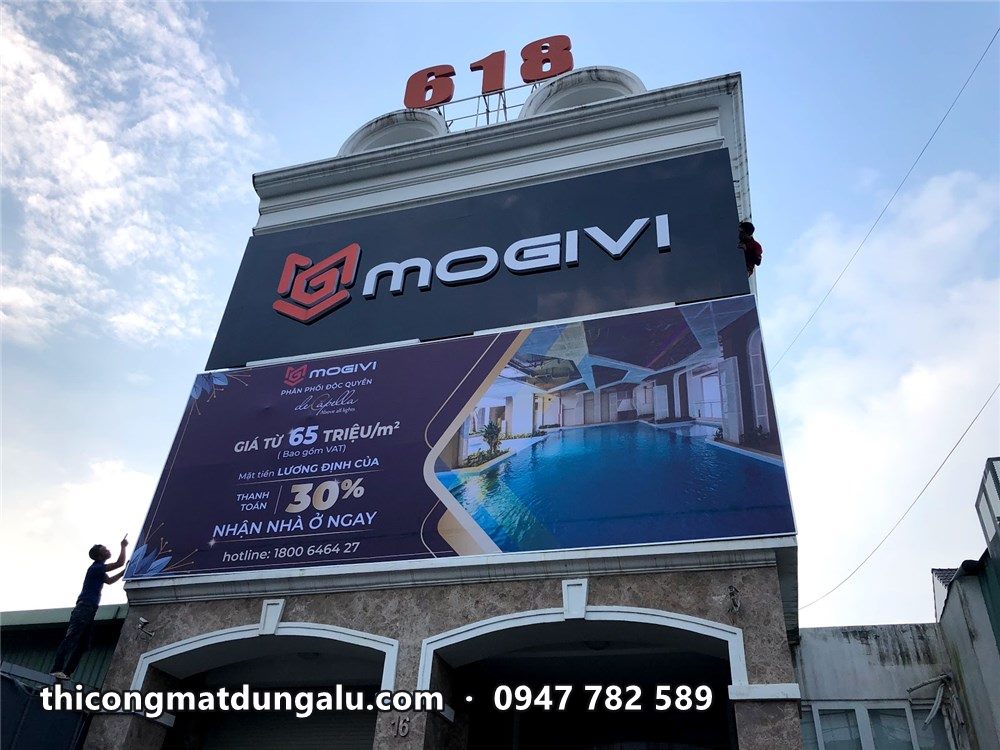 Tòa nhà với bảng hiệu Mogivi và bạt quảng cáo De Capella khổ lớn phủ mặt tiền