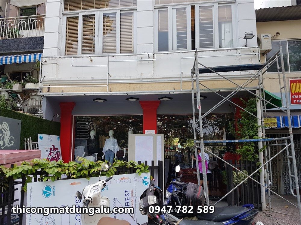 Thợ trên giàn giáo ốp tấm phía trên tủ kính shop thời trang