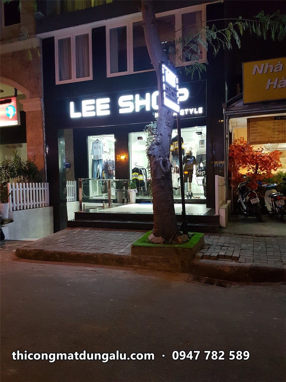 Lee Shop ban đêm, chữ trắng trên nền đen và hộp đèn đứng ở góc