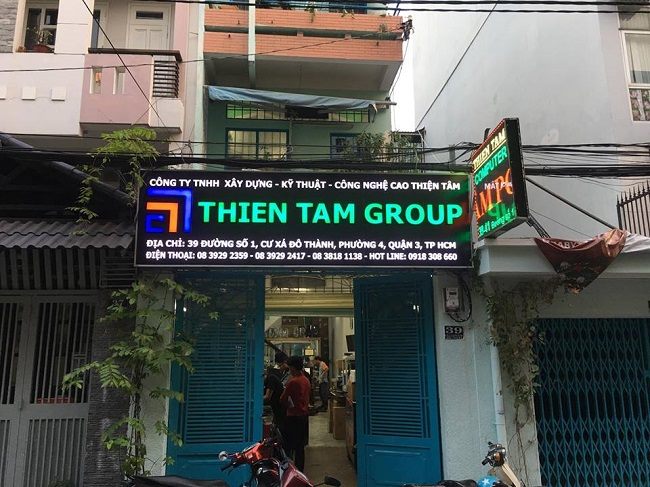 Bảng hiệu Thiên Tâm Group trên mặt tiền nhà phố, chữ phát sáng xanh trên nền đen