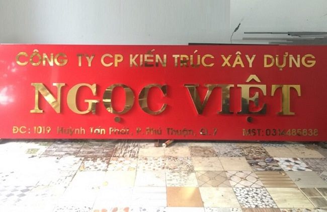Biển tên công ty kiến trúc xây dựng Ngọc Việt chữ inox vàng trên nền đá đỏ