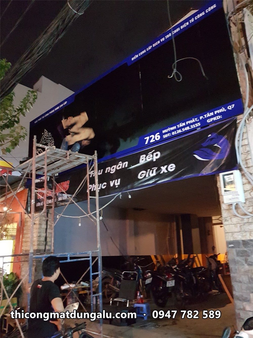Bảng hiệu PSM Gaming đang lắp ban đêm trên giàn giáo
