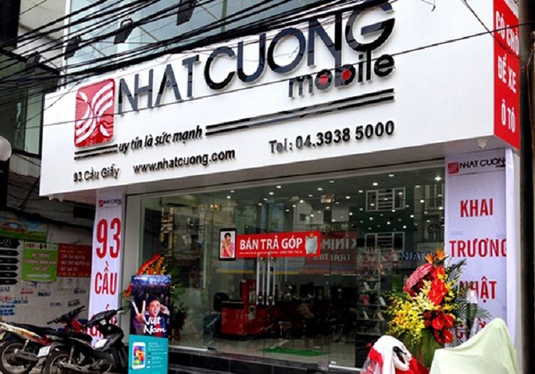 Mặt tiền cửa hàng Nhật Cường Mobile nền trắng, chữ nổi đỏ và biển dọc khai trương