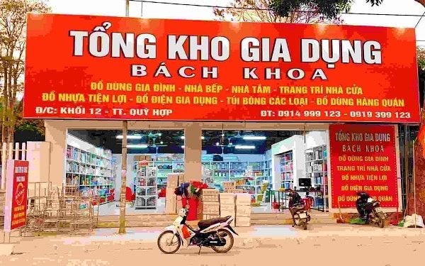 Bảng hiệu bạt Tổng kho gia dụng Bách Khoa nền đỏ khổ lớn ghi nhiều nhóm hàng phía trên cửa hàng