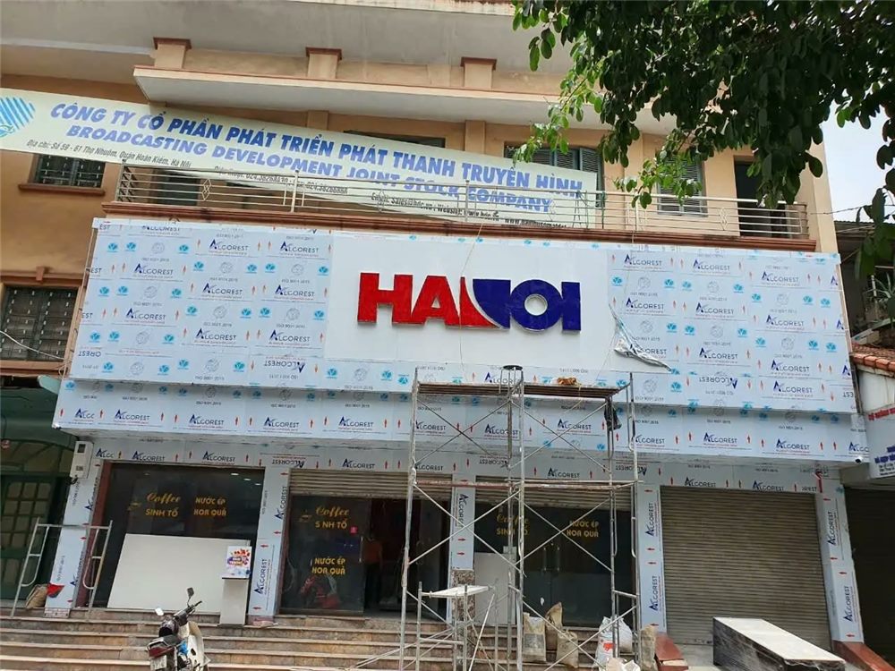 Mặt tiền cửa hàng máy tính đang ốp alu còn phim bảo vệ, chữ nổi đỏ đã gắn, giàn giáo phía trước