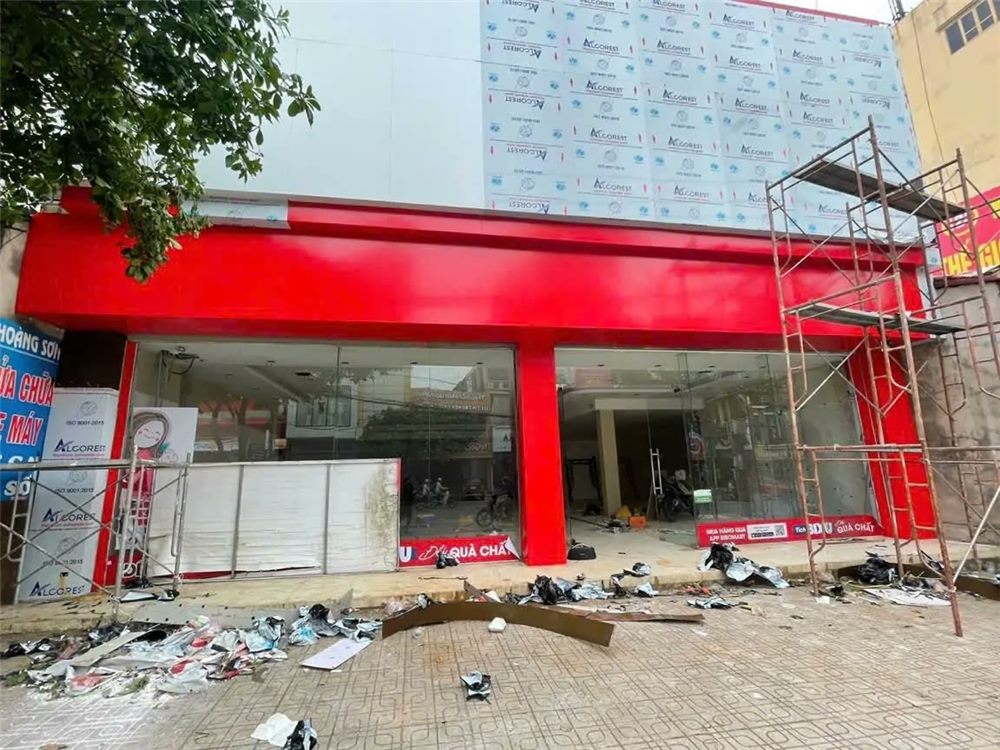 Khung ốp alu đỏ ôm quanh cửa kính tầng trệt cửa hàng máy tính đang thi công