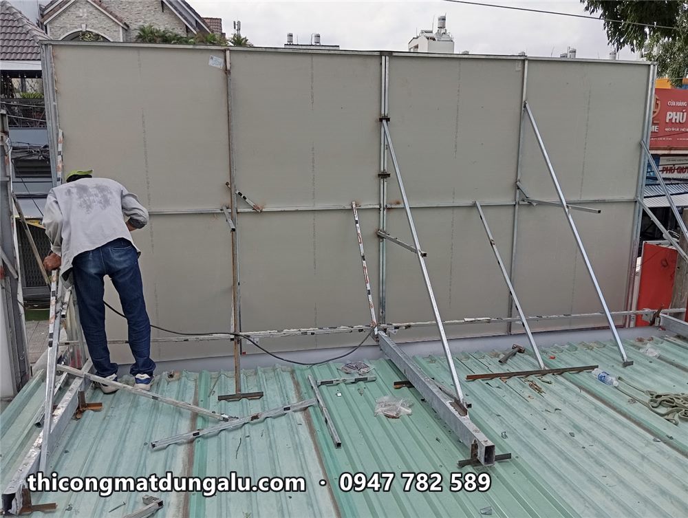Thợ dựng khung biển trên mái tôn, tấm mặt biển xám đã lắp