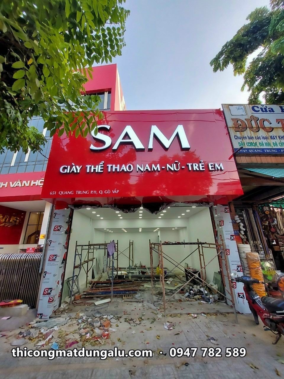 Cửa hàng SAM giày thể thao nam nữ trẻ em với biển đỏ chữ trắng, đang thi công