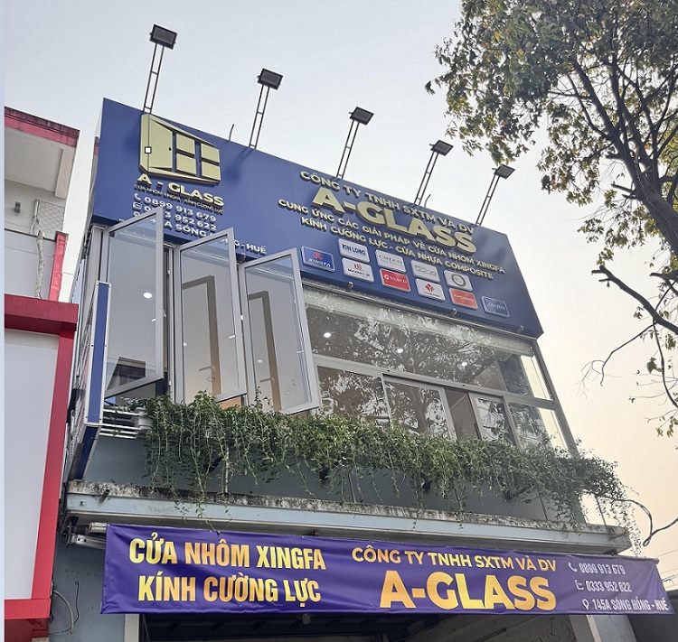 Cửa hàng nhôm kính nhà phố với bảng xanh dương, cửa mẫu trên ban công và đèn pha trên nóc