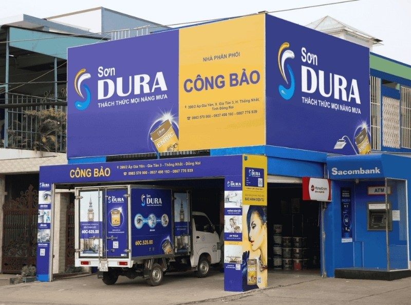 Nhà phân phối sơn Dura ở góc phố với bảng xanh tím và vàng chạy hai mặt