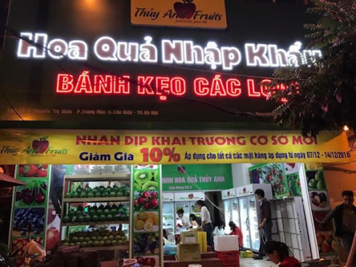 Cửa hàng hoa quả nhập khẩu về đêm với chữ LED trắng và đỏ, băng rôn khai trương