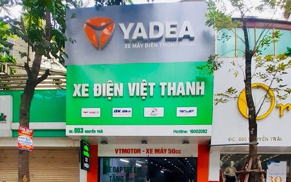 Đại lý xe máy điện Yadea với bảng xám bạc của hãng và bảng xanh lá tên cửa hàng