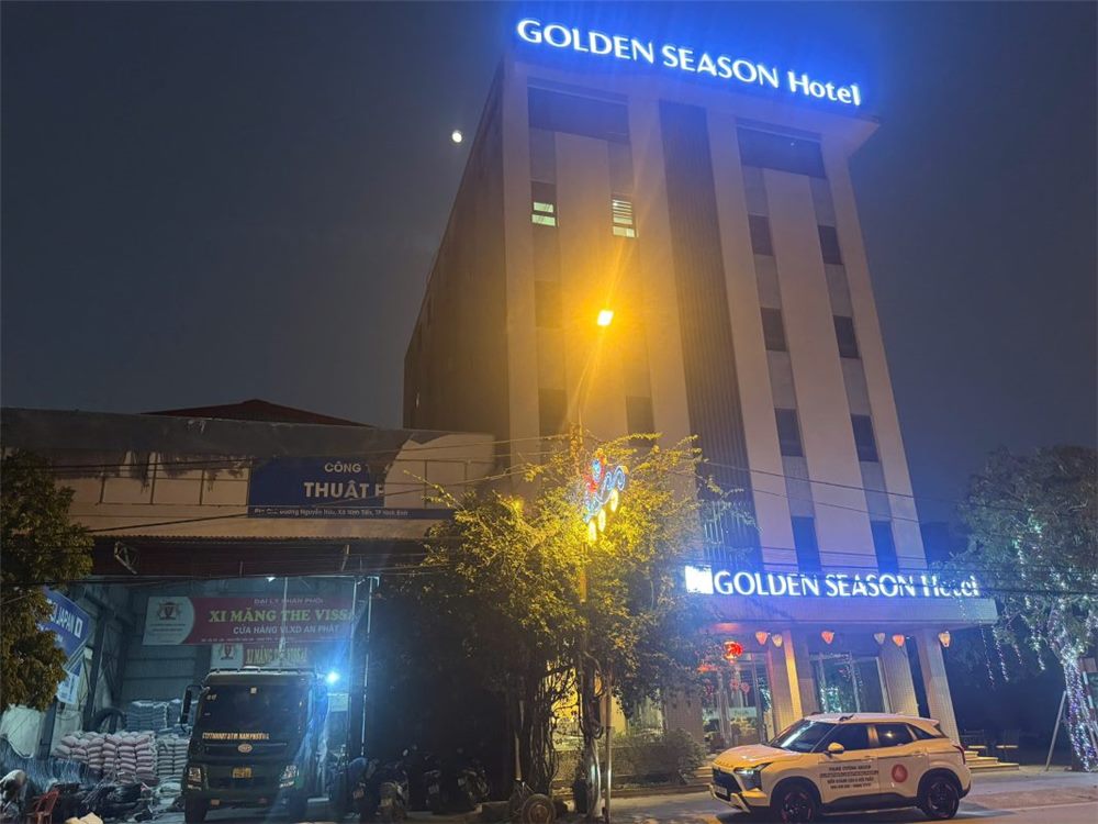 Khách sạn Golden Season về đêm với chữ nổi xanh sáng trên nóc và tên lặp lại ở sảnh tầng trệt