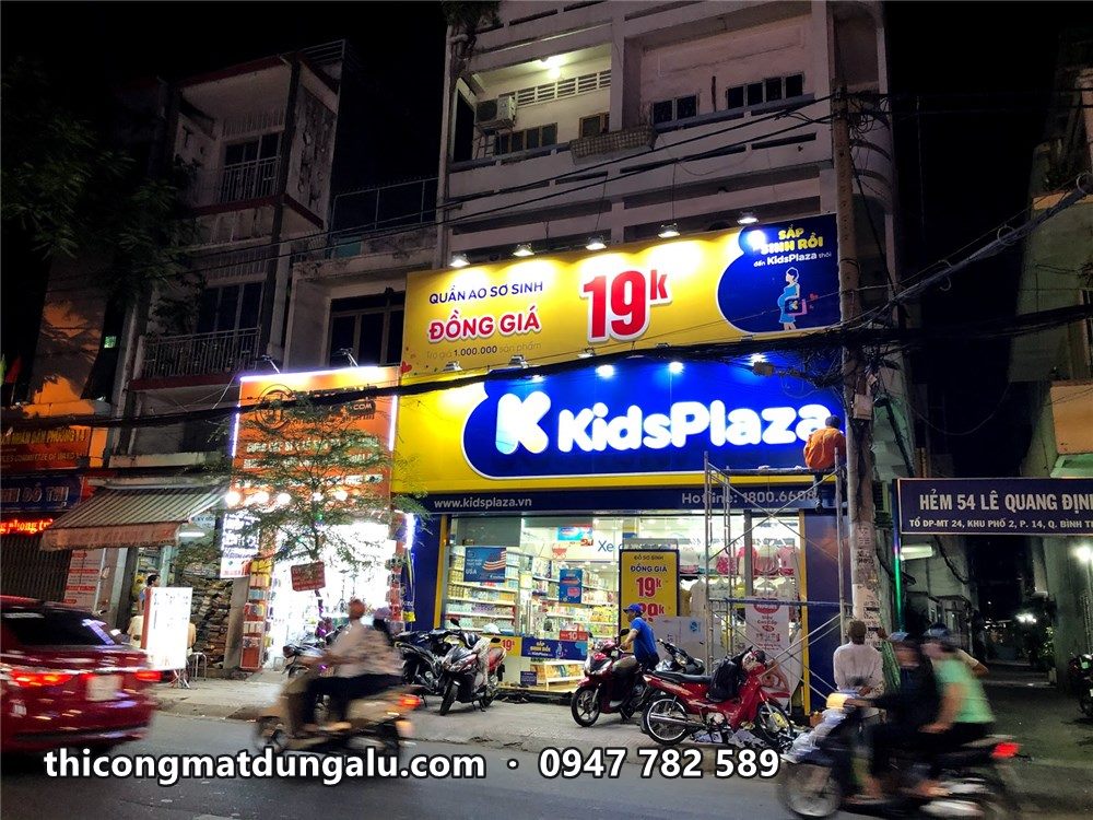 Cửa hàng KidsPlaza ban đêm với biển xanh vàng sáng đèn ở góc phố