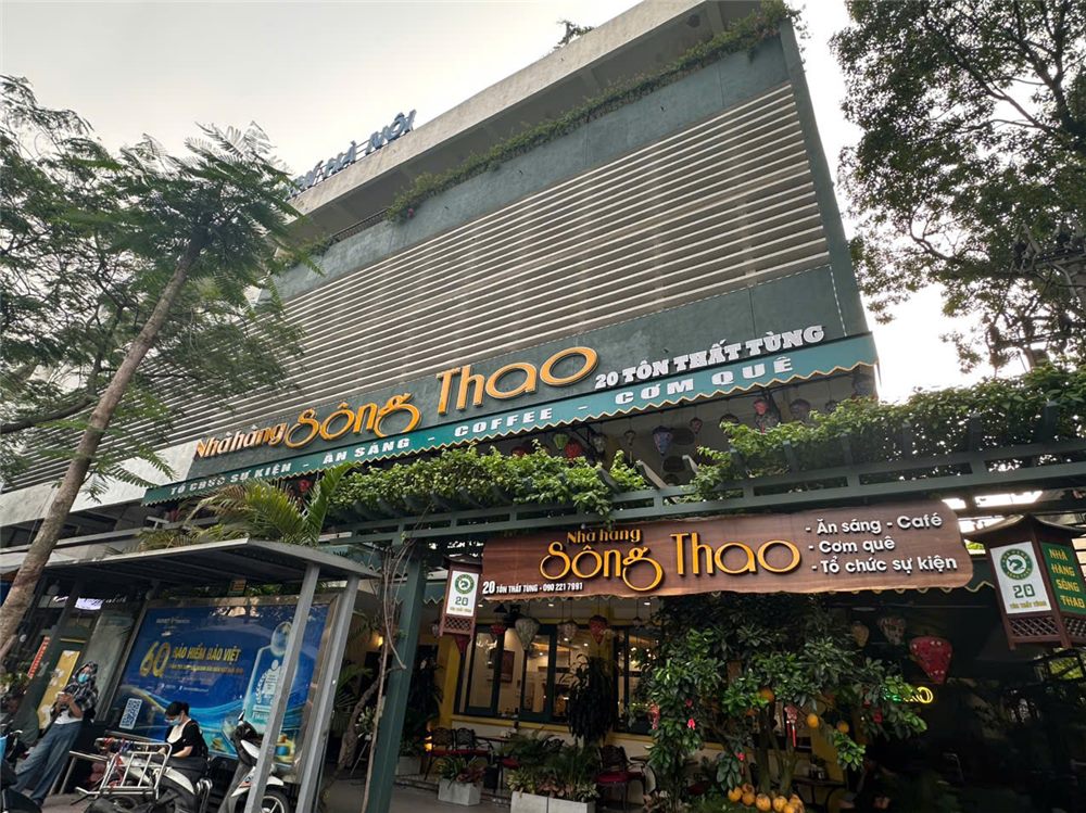 Nhà hàng nhiều cây xanh với bảng hiệu chữ nổi màu trầm