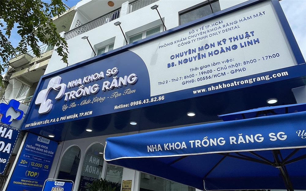 Bảng hiệu nha khoa nền xanh đậm kèm thông tin bác sĩ và giờ làm việc