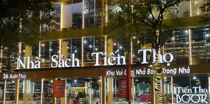 Nhà sách nhiều tầng về đêm với chữ trắng gắn trên mặt kính và dây đèn trang trí