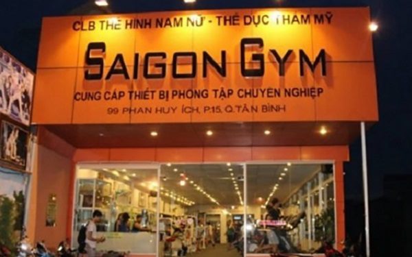 Phòng gym nền cam với chữ nổi đen và mặt tiền kính sáng đèn