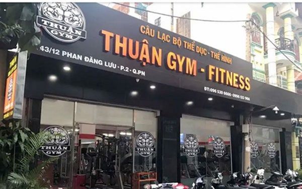 Câu lạc bộ thể hình nền đen chữ nổi cam, mặt kính thấy máy tập