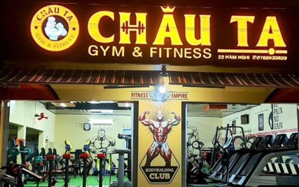 Phòng gym về đêm với chữ nổi vàng sáng mặt và logo tròn