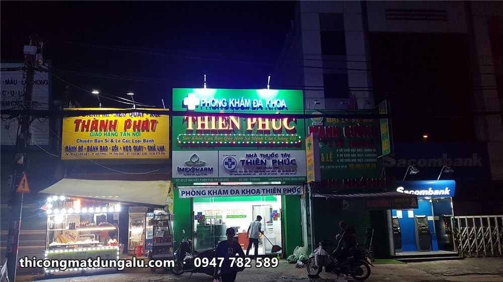 Phòng khám Thiên Phúc nhìn từ bên kia đường ban đêm giữa dãy cửa hàng