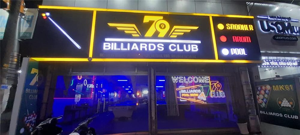 Bảng hiệu billiards club ban đêm với logo cánh, chữ sáng và các ô snooker carom pool
