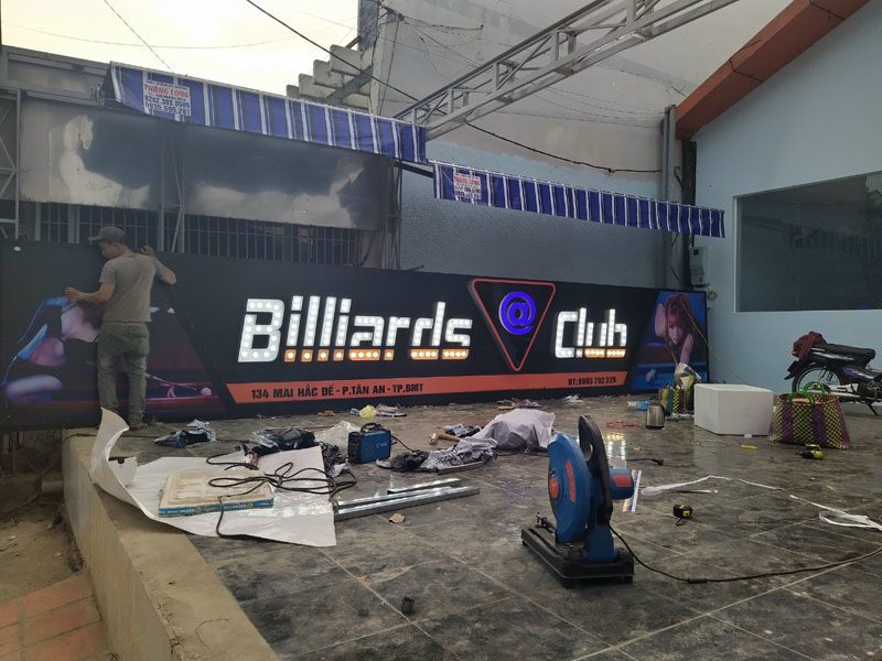 Bảng hiệu billiards club nền đen đang được thi công, đặt dưới nền nhà