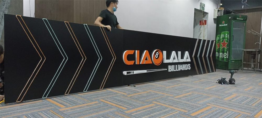 Vách đen trang trí họa tiết mũi tên với logo quán bida đang được dựng trong nhà
