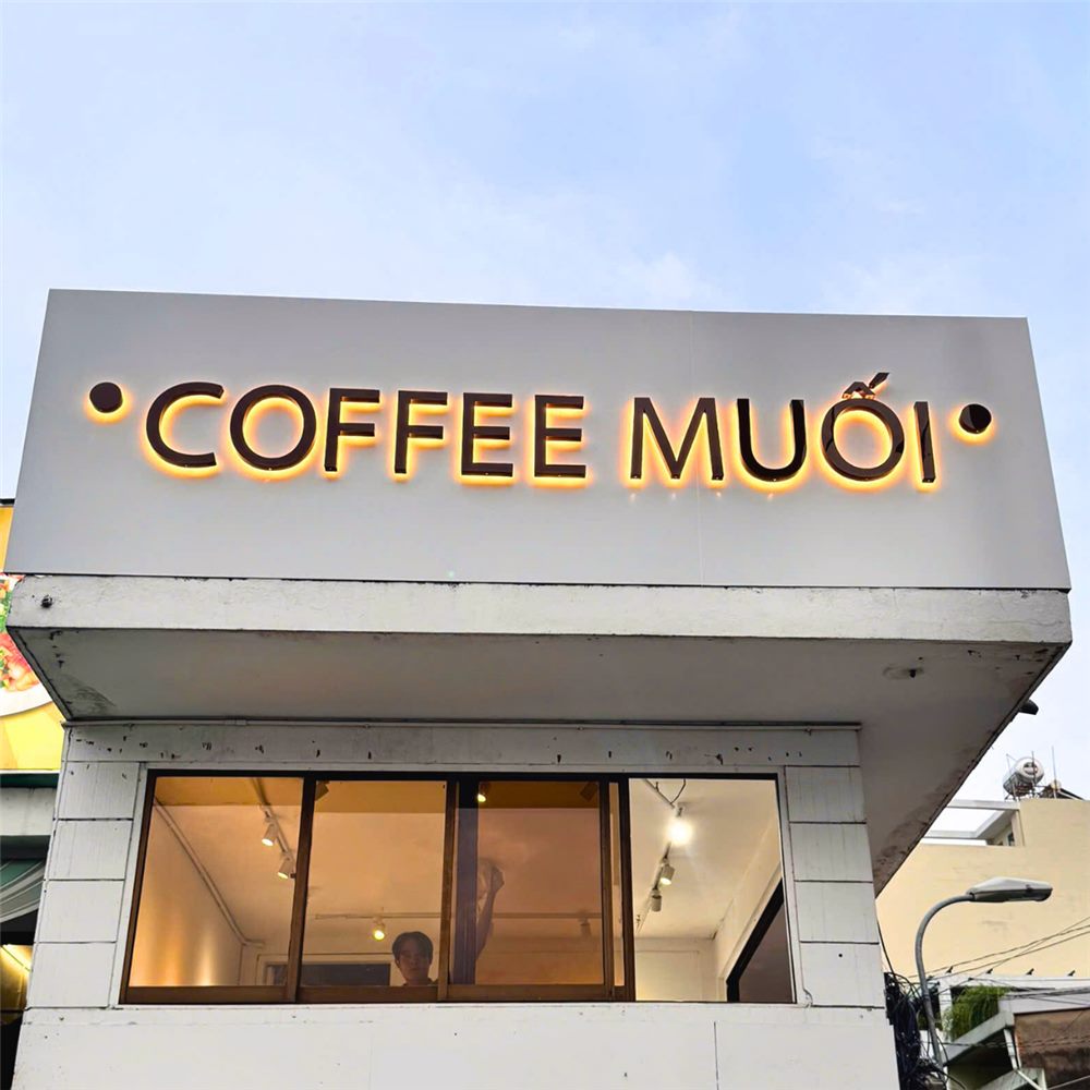 Chữ nổi Coffee Muối hắt sáng chân trên nền tường trắng