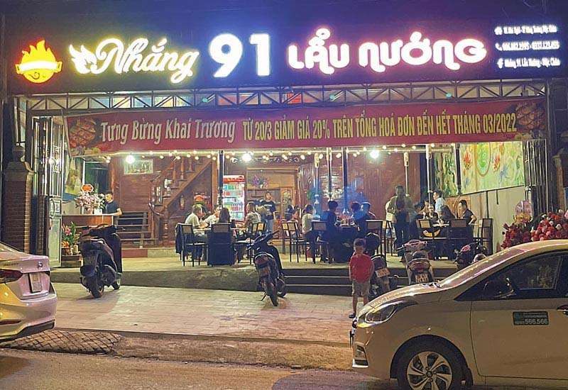 Quán Nhắng 91 lẩu nướng về đêm với chữ nổi phát sáng và khu bàn ngoài trời