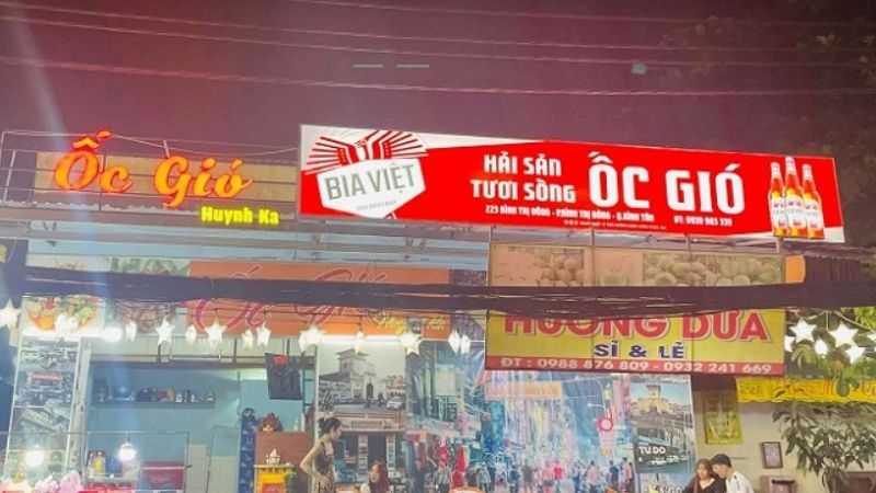 Dãy quán ốc về đêm với bảng đỏ, chữ nổi và logo hãng bia