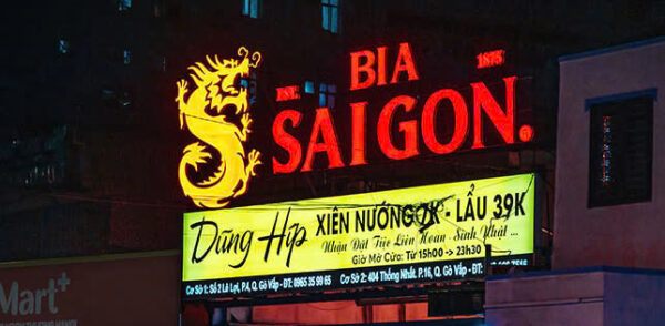 Bảng hiệu Bia Sài Gòn đỏ với hình rồng vàng và bảng phụ vàng ghi món nhậu, giá lẩu
