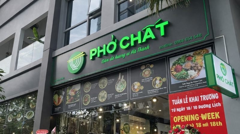 Mặt tiền quán Phở Chất với logo xanh, chữ nổi phát sáng và dải hình món ăn