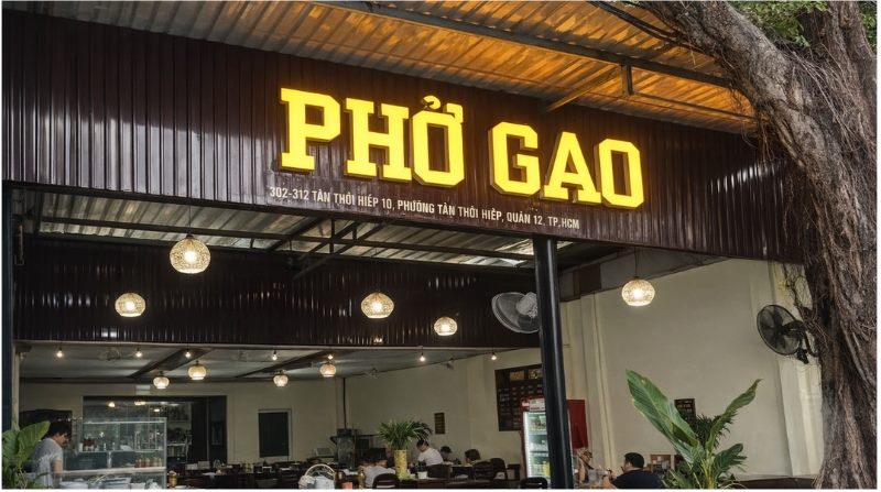Bảng hiệu quán Phở Gạo chữ nổi vàng phát sáng trên nền tôn sẫm màu