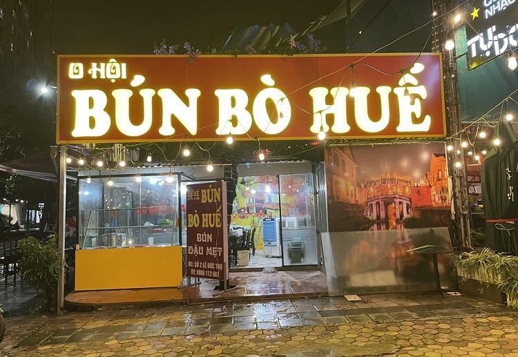 Bảng hiệu bún bò Huế O Hội chữ nổi trắng phát sáng trên nền đỏ nâu về đêm