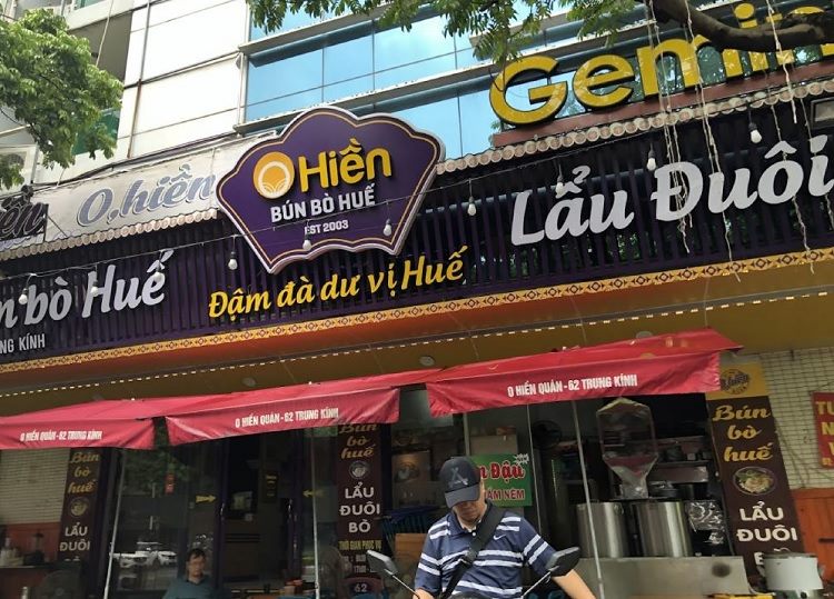 Mặt tiền quán O Hiền bún bò Huế với logo tím và chữ trắng trên nền đen