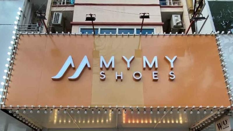 Bảng hiệu MyMy Shoes nền cam đất, chữ nổi trắng và viền bóng đèn