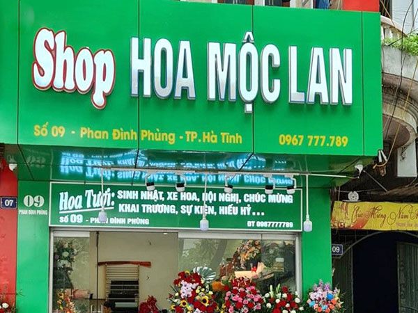 Shop hoa nền xanh lá với chữ nổi trắng và dải dịch vụ hoa tươi