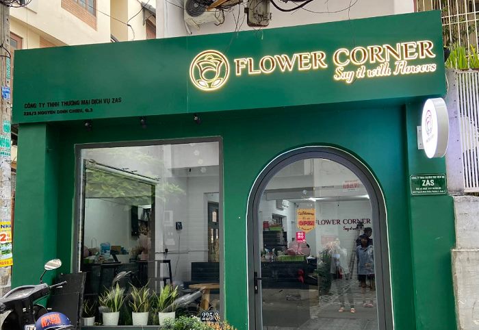 Mặt tiền shop hoa ốp xanh lá đậm, chữ vàng hắt sáng và cửa vòm kính