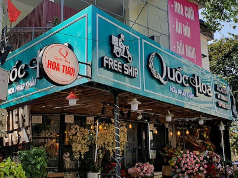 Shop hoa góc phố với bảng hiệu xanh ngọc, logo tròn và nhiều hoa trưng bày