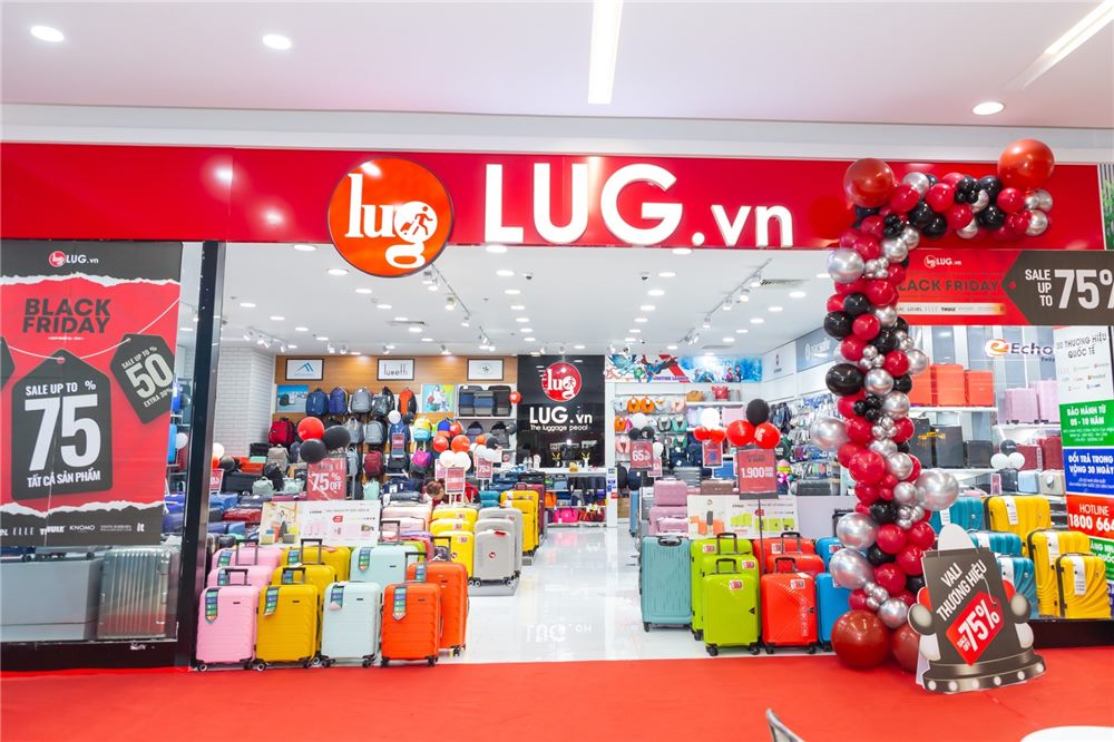 Cửa hàng LUG.vn nền đỏ với logo tròn và chữ trắng, vali nhiều màu xếp sát lối vào