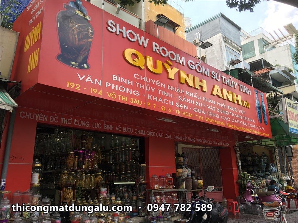 Showroom gốm sứ thủy tinh Quỳnh Anh bảng hiệu đỏ chữ vàng, hàng gốm trưng bày trước cửa