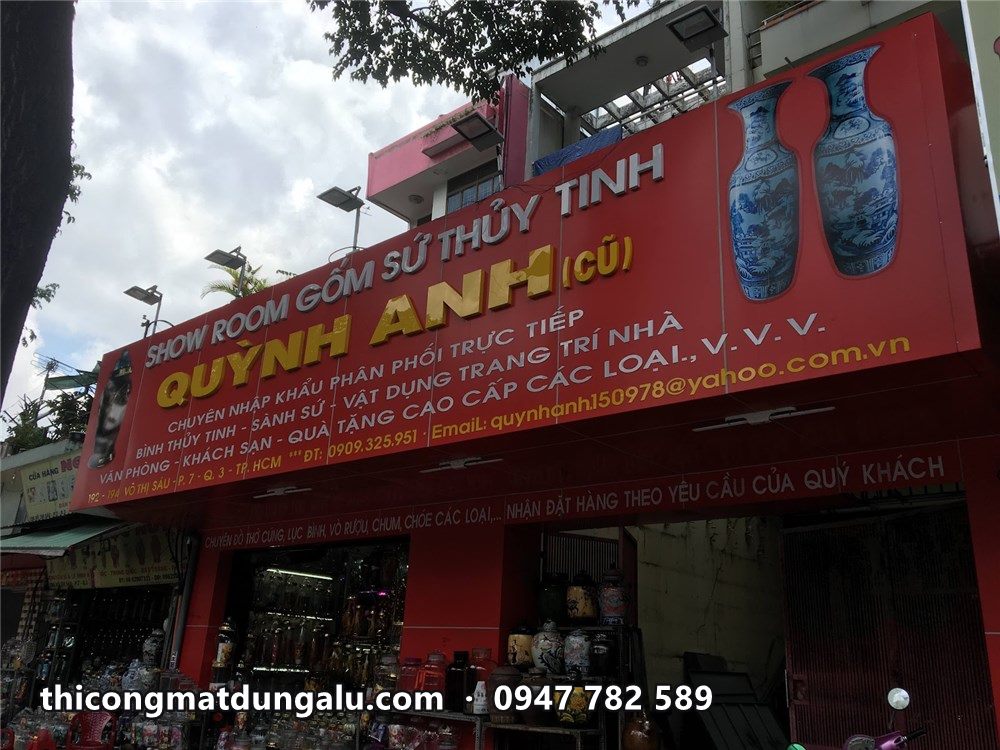 Bảng hiệu showroom gốm sứ Quỳnh Anh nền đỏ, hai bên có hình bình gốm lam