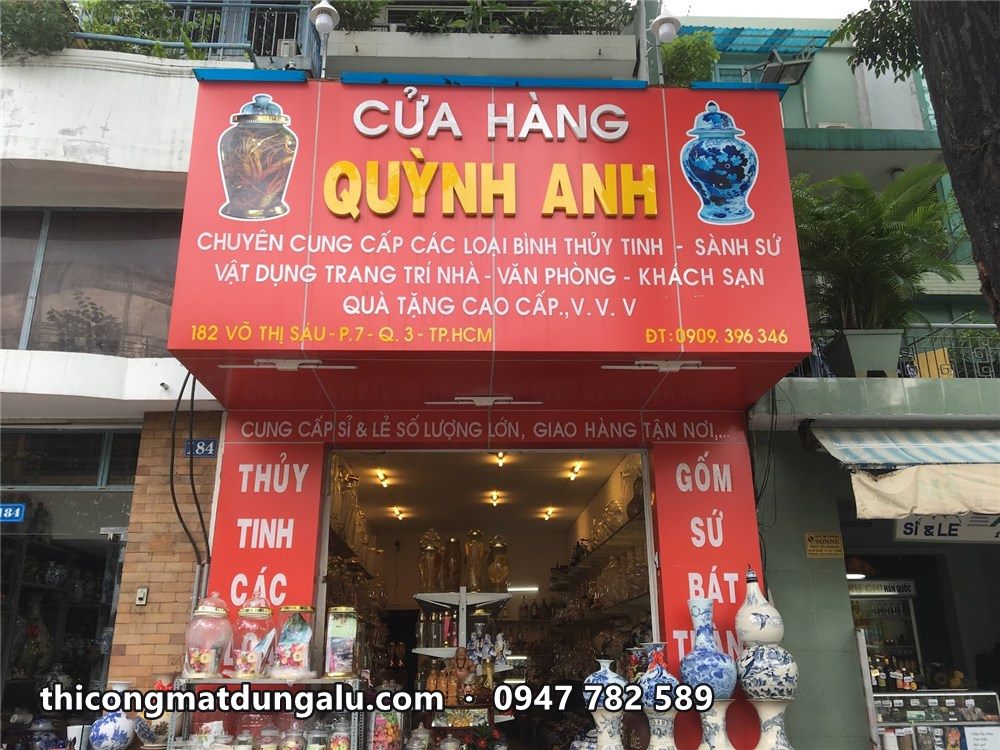 Cửa hàng Quỳnh Anh bảng hiệu đỏ, hàng gốm sứ lam trắng bày trước cửa
