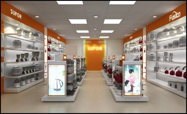 Bên trong showroom gia dụng với kệ trắng và mảng tường cam mang logo thương hiệu
