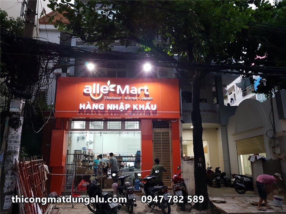 Mặt tiền Alle Mart Hàng nhập khẩu sáng đèn buổi tối dưới tán cây